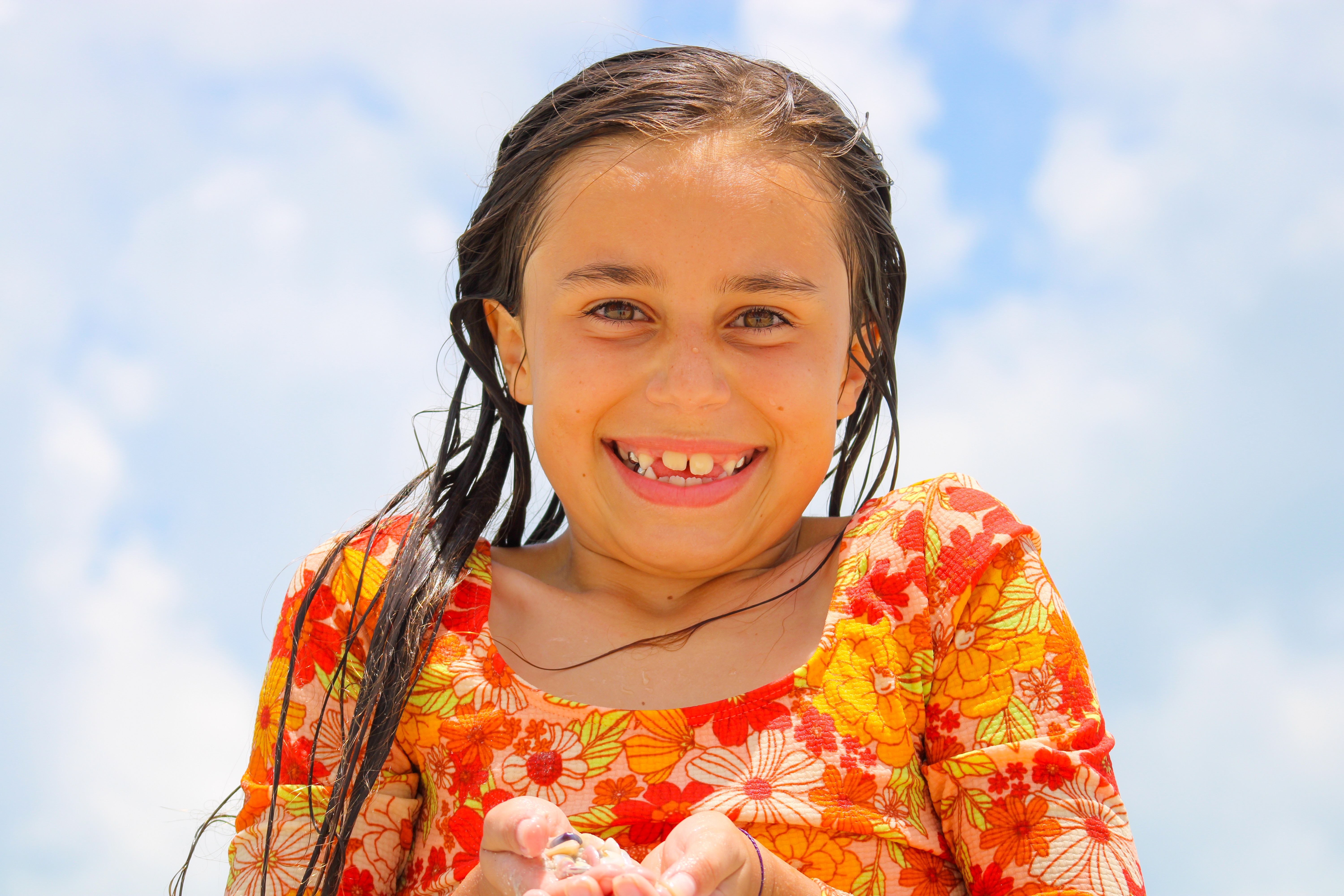 child holding sea shells and smiling