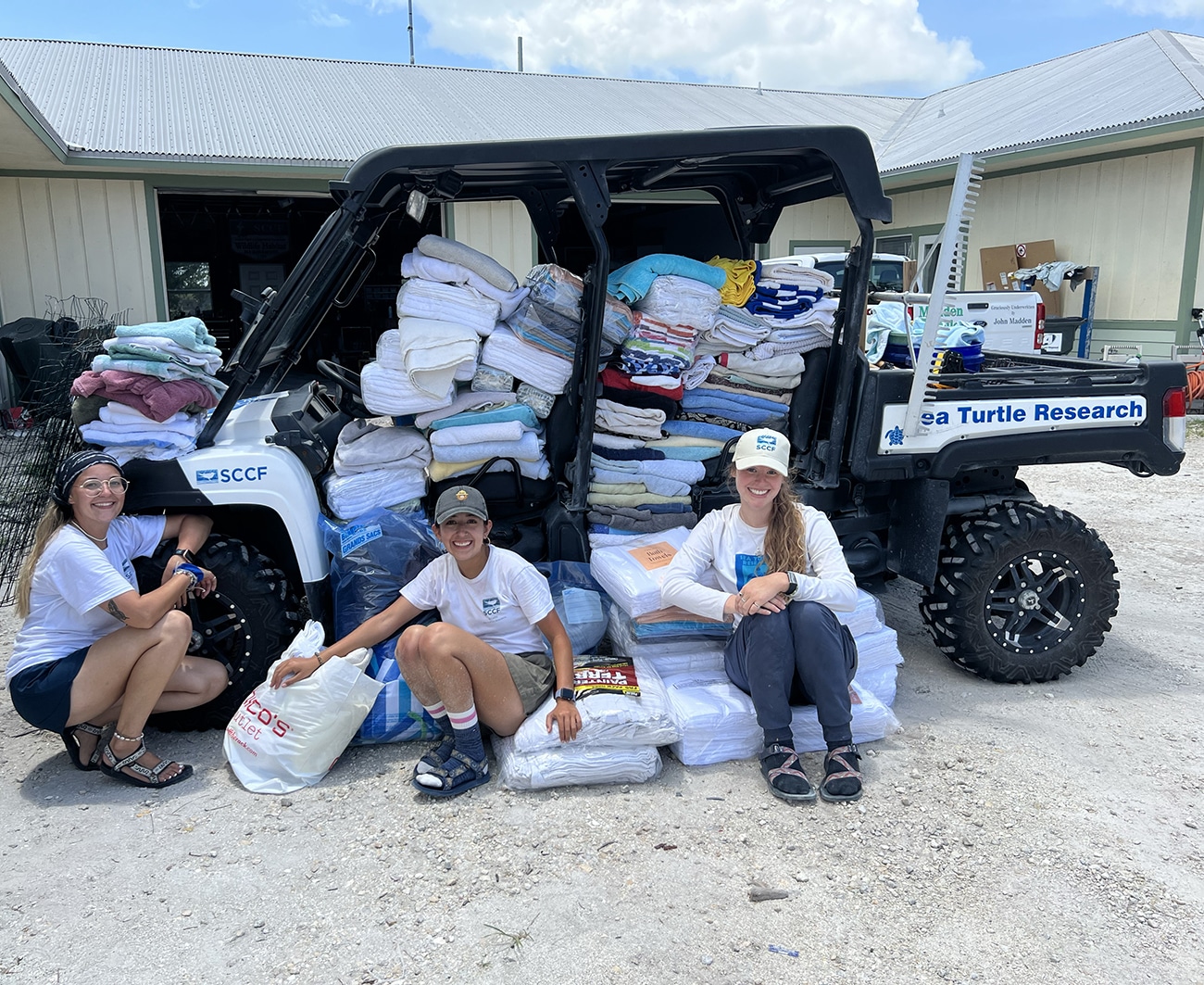 three people sitting on massive pile of towels for sea turtles