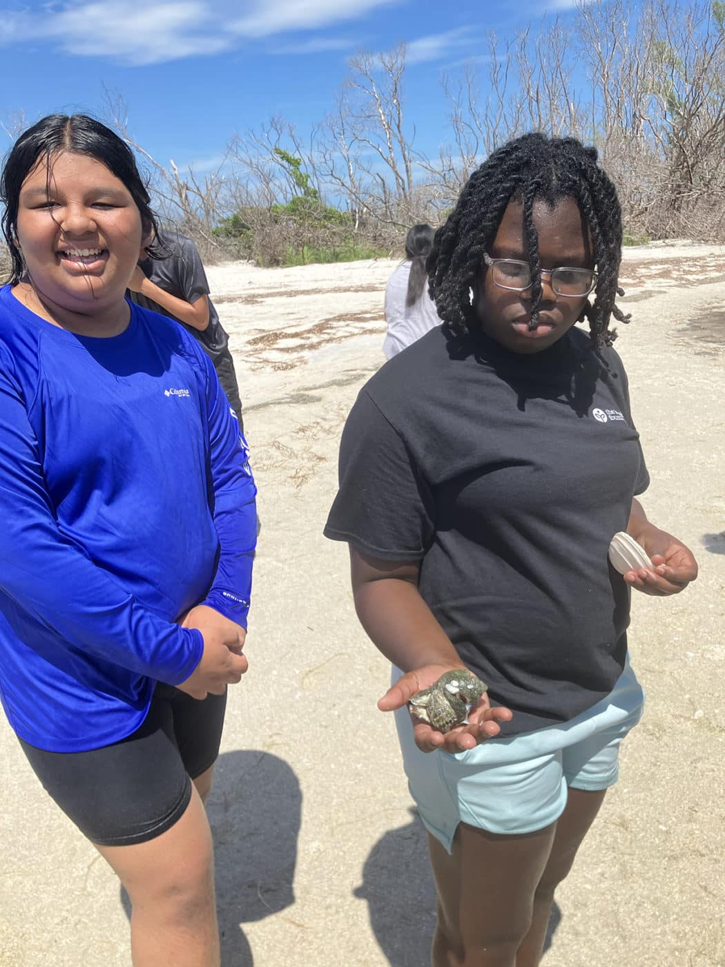 two girls holding objects on the beach