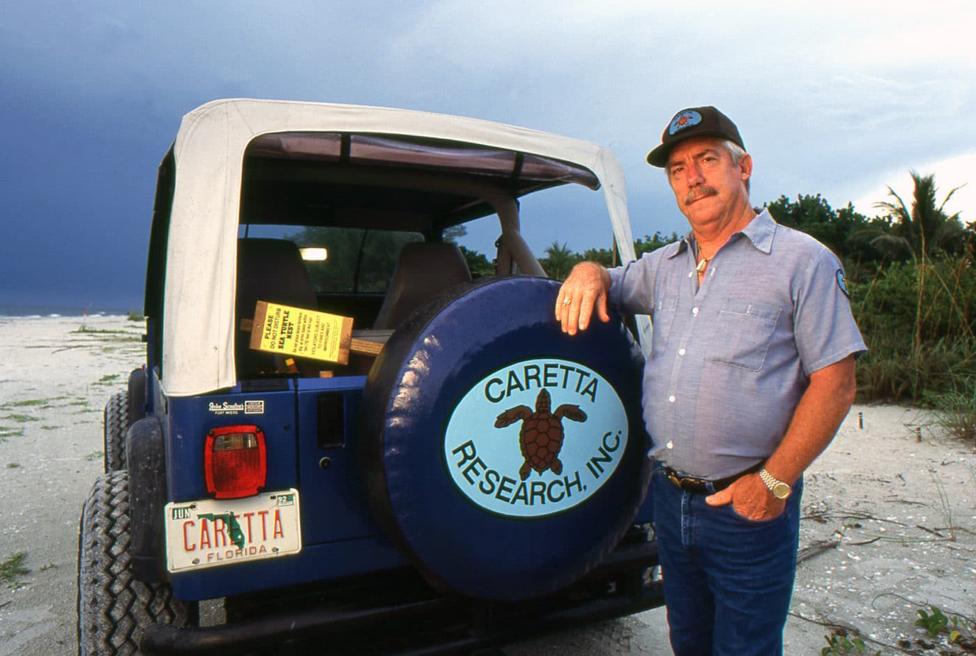 man standing on beach with vehicle that says 'caretta research inc'