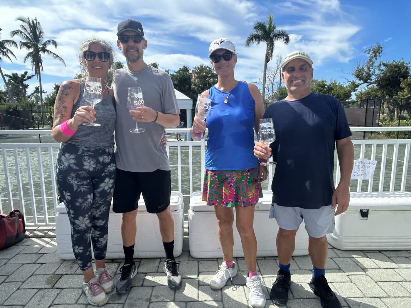 four people smiling outdoors holding wine glasses