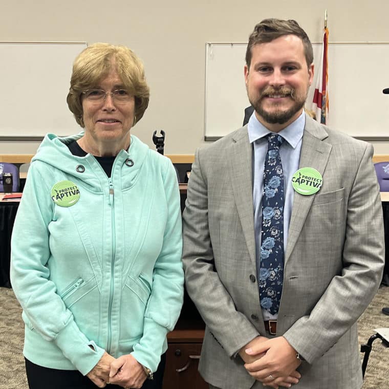 two people in a room smiling with buttons that read 'protect captiva'