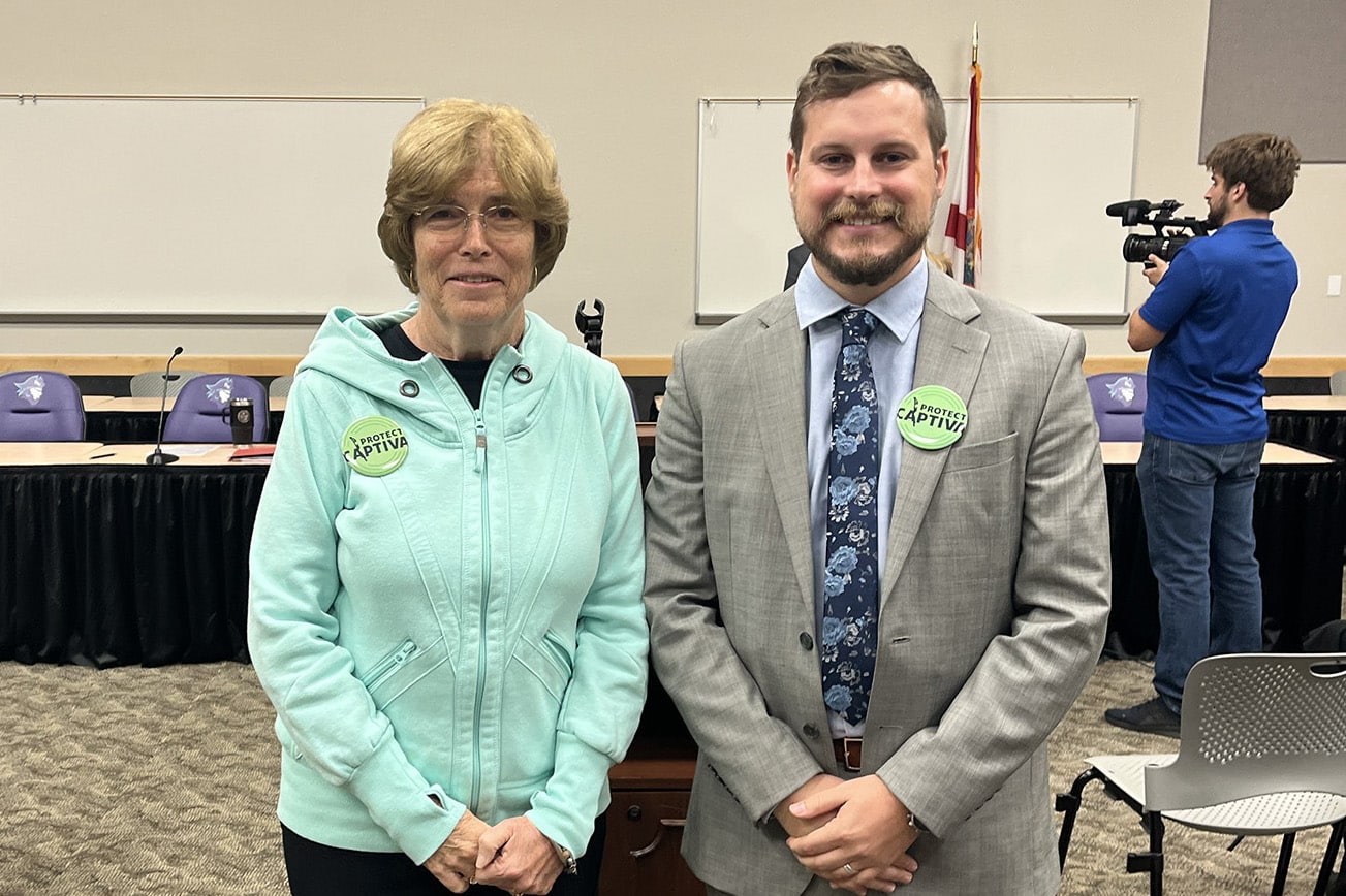 two people in a room smiling with buttons that read 'protect captiva'