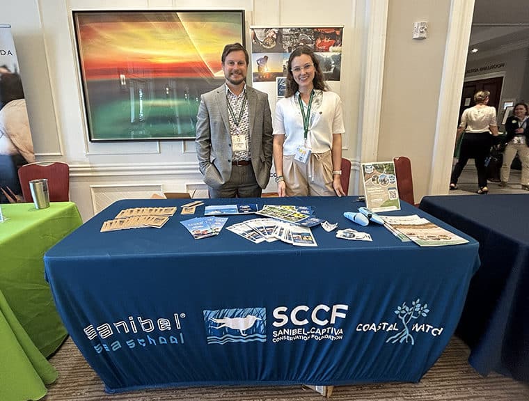 everglades conference 2024, two staff stand at SCCF table indoors