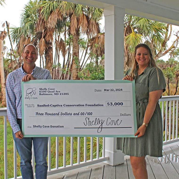 two people holding big check outdoors