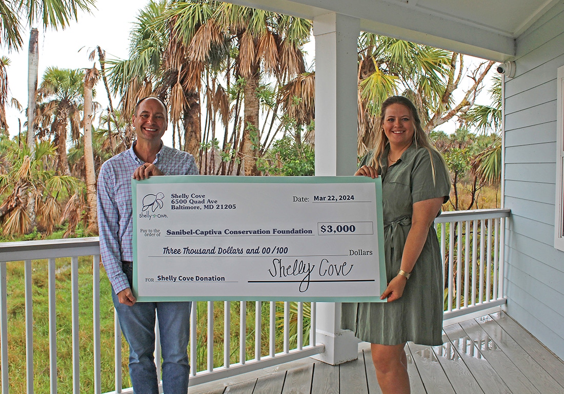 two people holding big check outdoors