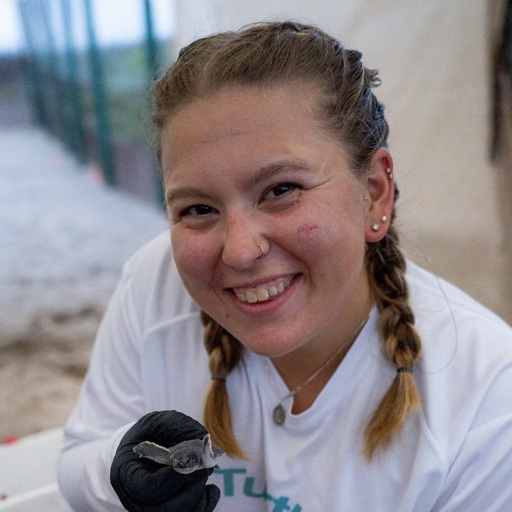 image of sea turtle intern smiling with baby hatchling sea turtle
