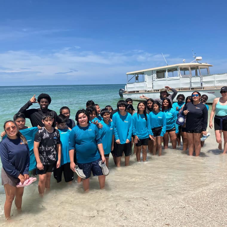 no child left on shore group of people standing in water in front of boat