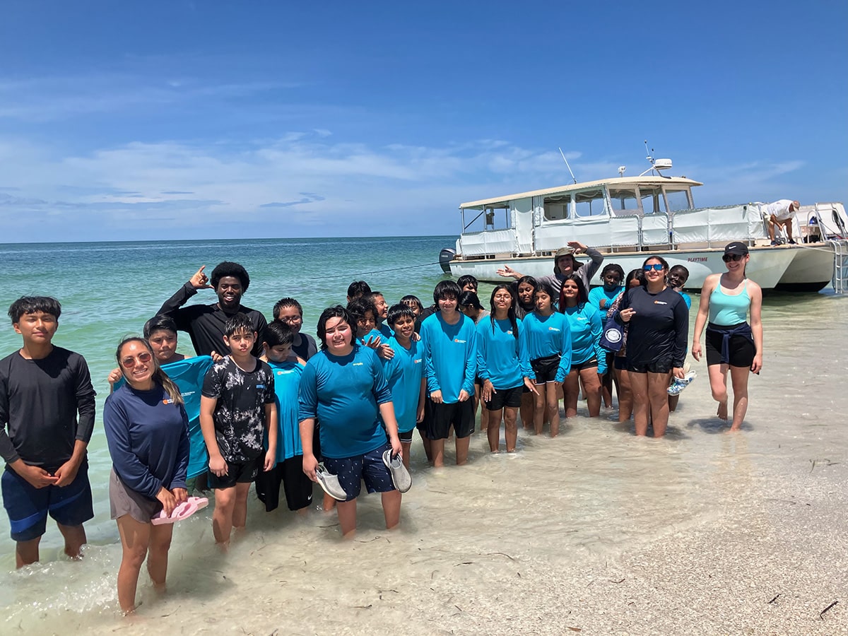 no child left on shore group of people standing in water in front of boat
