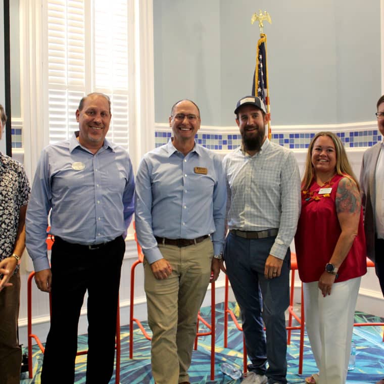 group of six people standing and smiling indoors