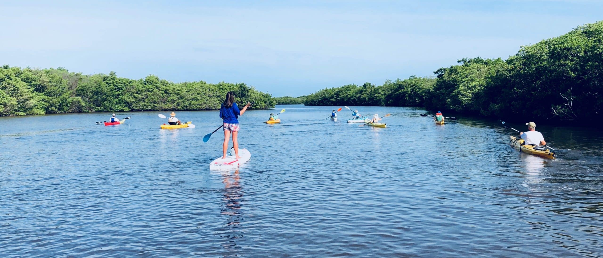 people on water with paddle boards and kayaks