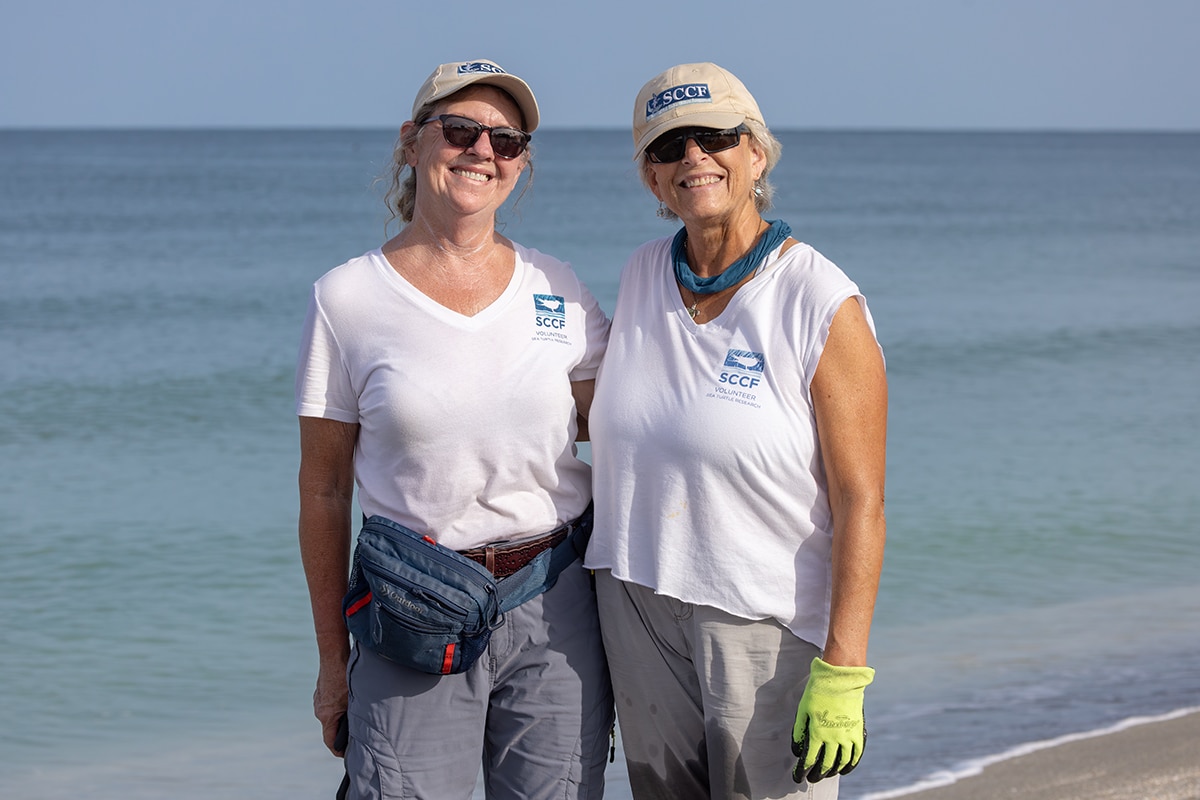 two sccf sea turtle volunteers smiling on the beach